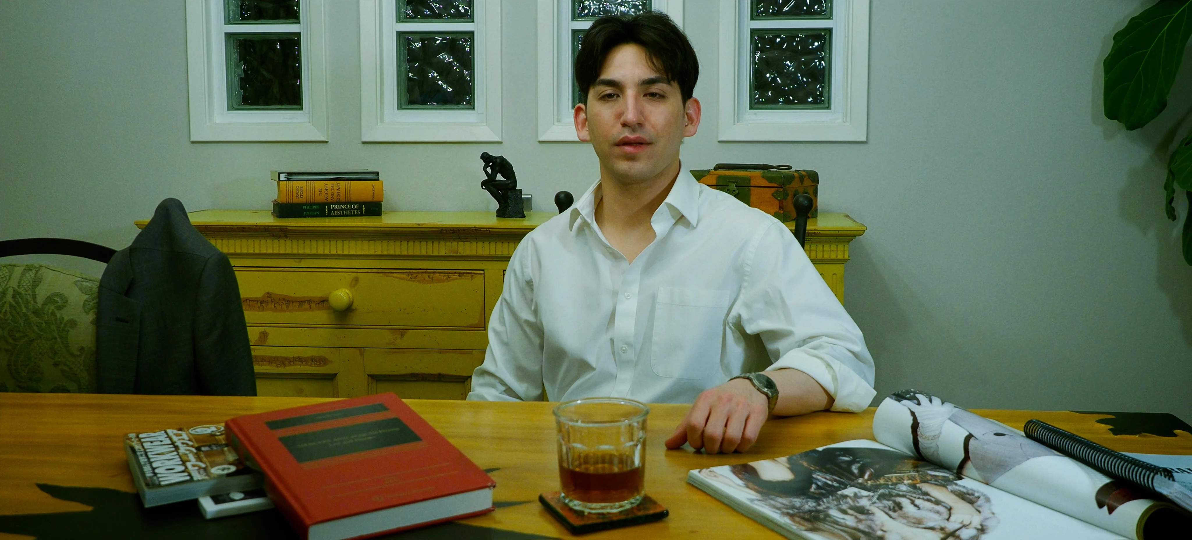 Ian Bloom as The Suit in Star Vehicle wearing a black suit and tie indoors